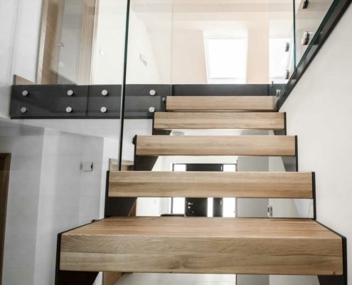 looking up and through the open steps of an oak and glass stair