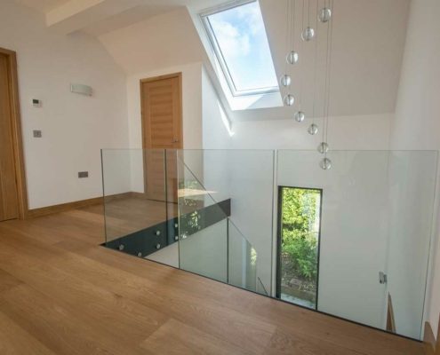 landing areas with sloping ceiling above and timber floor with frameless glass balustrade