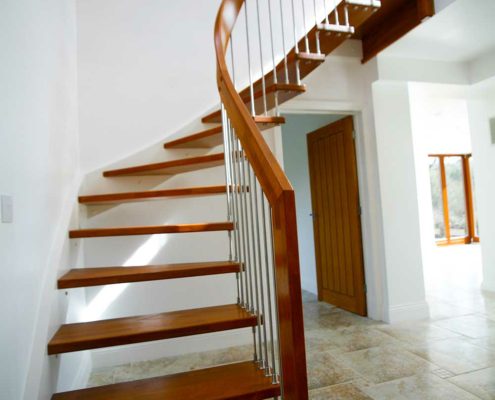 dark wooden floating stair with white wall behind