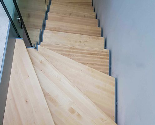 looking own on a maple step stair with glass balustrade