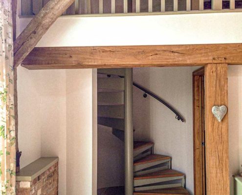 rustic barn conversion showing a spiral staircase leading to a mezzanine
