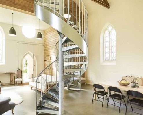 large grey steel spiral staircase with concrete floor below